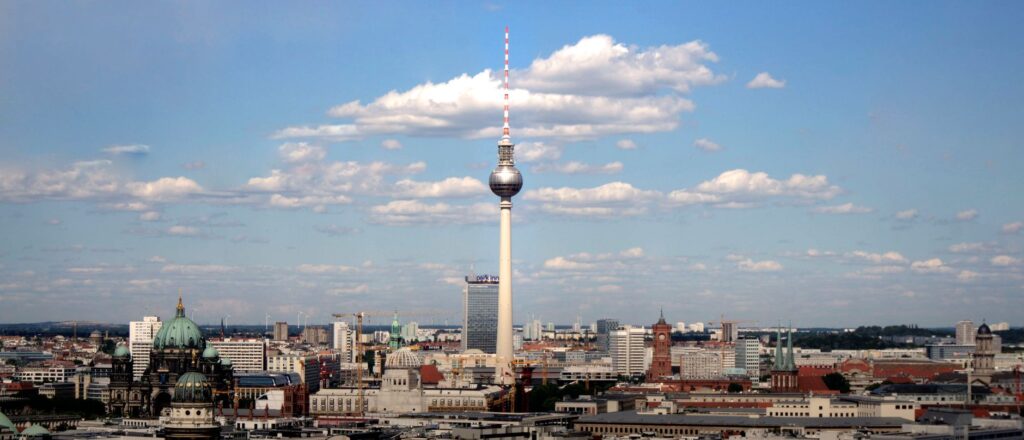 Panoramic view of Berlin's skyline with Fernsehturm TV tower under a clear blue sky.