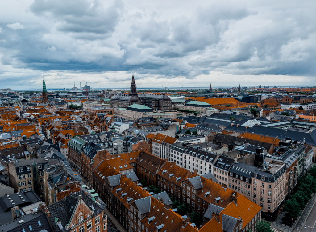 Aerial photo of Copenhagen showing historic rooftops under a cloudy sky.