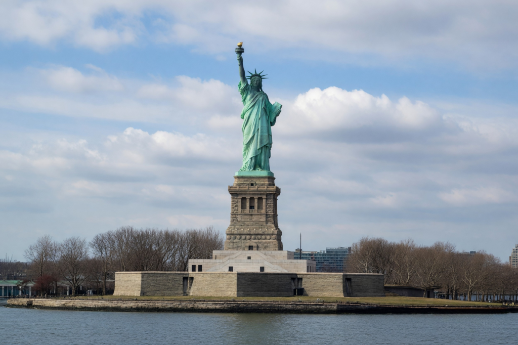The iconic Statue of Liberty under a cloudy blue sky in New York City.