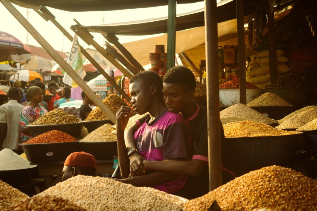 Vibrant market in Lagos featuring local traders surrounded by colorful grains and spices.