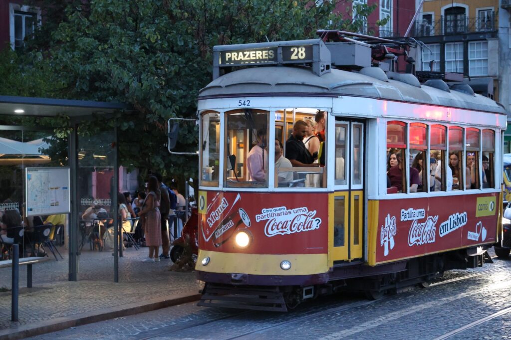 A classic Lisbon tram filled with passengers navigating through the city's historic streets at night.