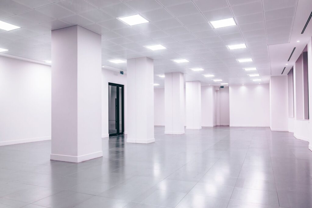 Wide-angle view of a modern minimalist white office space with clean lines and ample lighting.