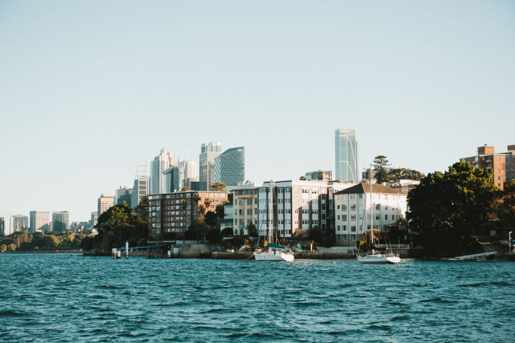 Scenic view of Sydney skyline across the water with boats in the foreground, highlighting urban architecture.
