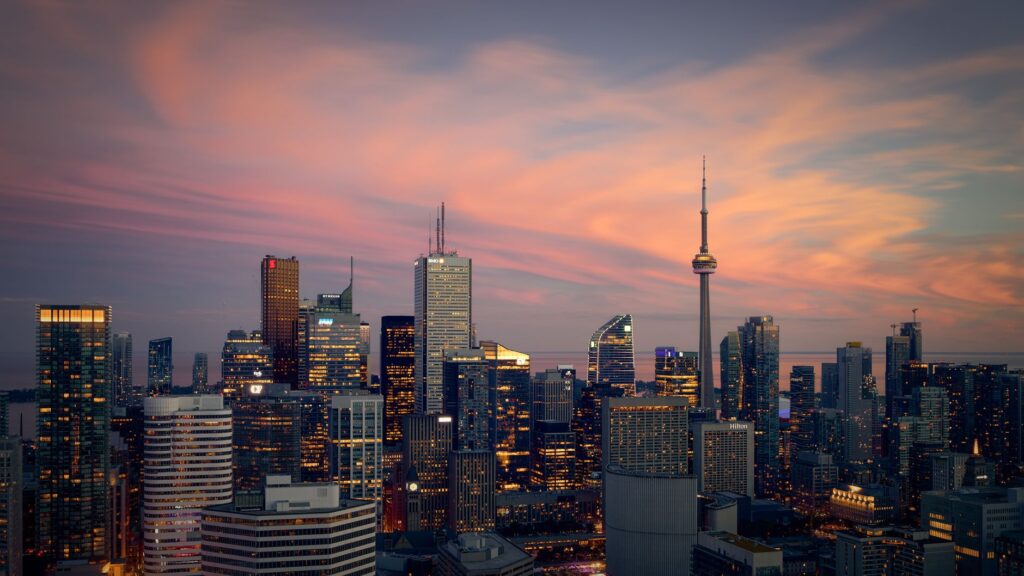Capture of the Toronto skyline at sunset, highlighting modern skyscrapers and the CN Tower.