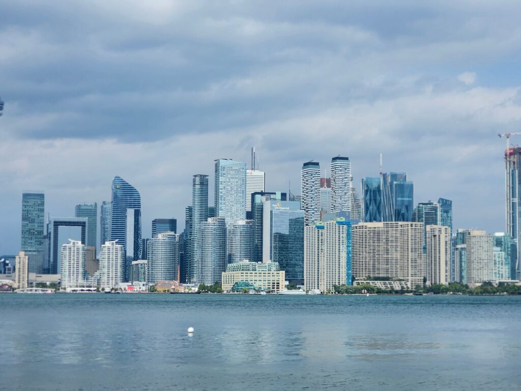 Stunning view of Toronto skyline featuring modern skyscrapers and Lake Ontario under cloudy skies.