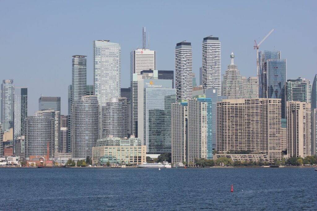 A clear view of Toronto's skyline with modern skyscrapers reflecting on a calm lake.