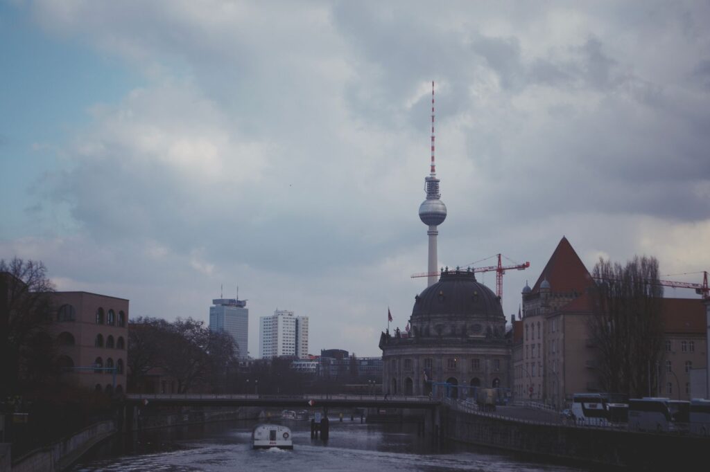 Stunning view of Berlin's iconic TV Tower over a serene river, showcasing the city's urban landscape.