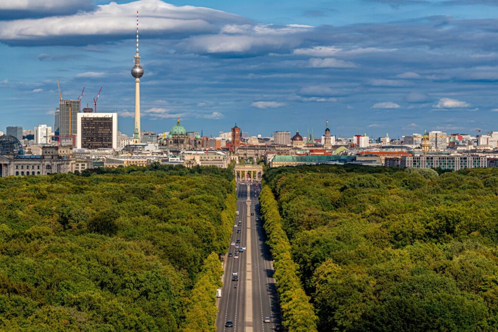 Stunning aerial view of Berlin's skyline with landmarks like Brandenburg Gate and Fernsehturm under blue sky.