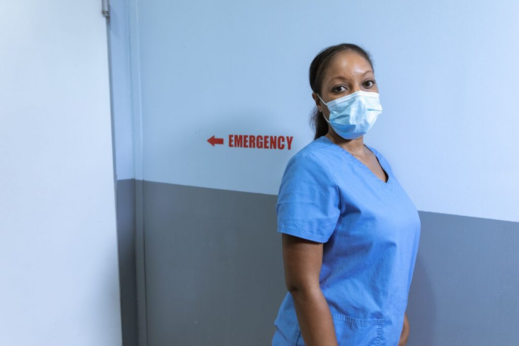 Nurse wearing mask in hospital emergency corridor for safety.